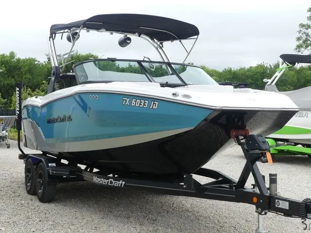 Slide: The Image of 2020 MasterCraft NXT22 boat on trailer, blue and white, parked outdoors. - 5