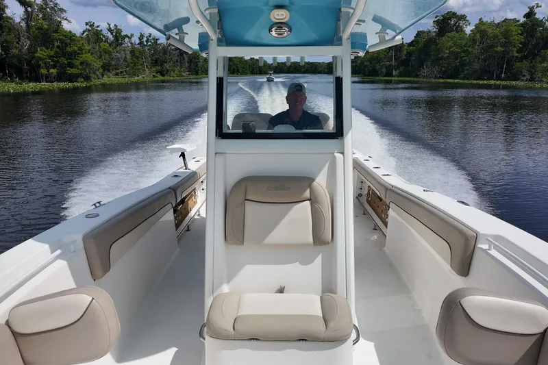 Slide: The Image of 2026 NAUTIC STAR 28 XS boat cruising on a scenic river with lush greenery. - 11