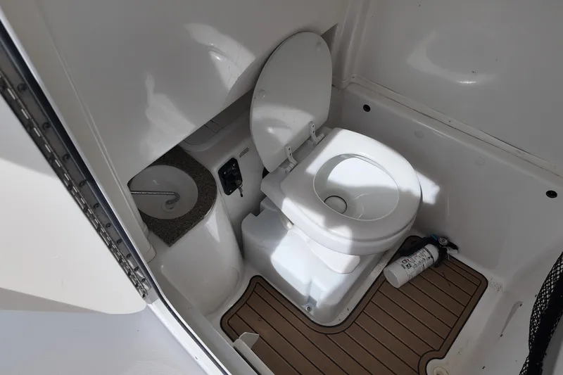 Slide: The Image of 2026 NAUTIC STAR 28 XS boat bathroom with toilet and sink, featuring wood-style flooring. - 14
