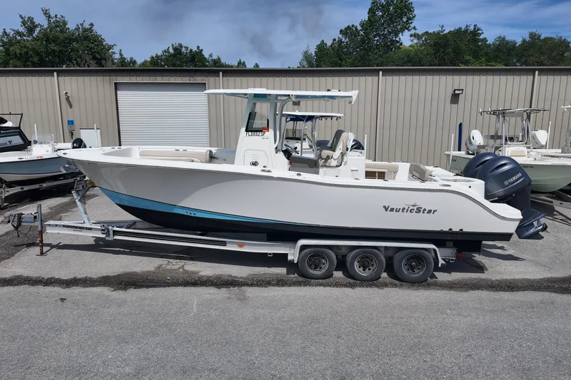 Slide: The Image of 2026 NAUTIC STAR 28 XS boat on trailer, parked outdoors near storage facility. - 3