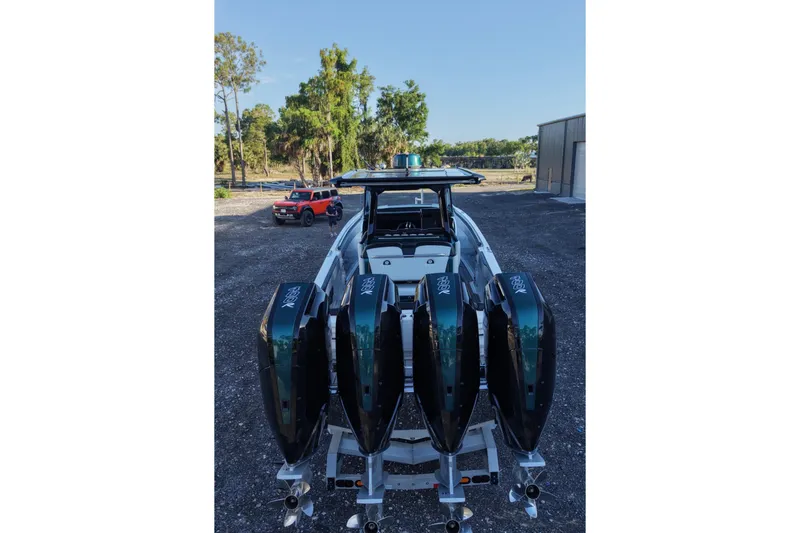 Slide: The Image of 2024 Nor-Tech 400 Supersport boat with four powerful outboard engines, parked outdoors. - 14