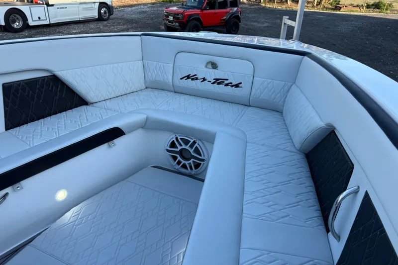 Slide: The Image of 2024 Nor-Tech 400 Supersport boat interior with white quilted seating and speaker. - 62