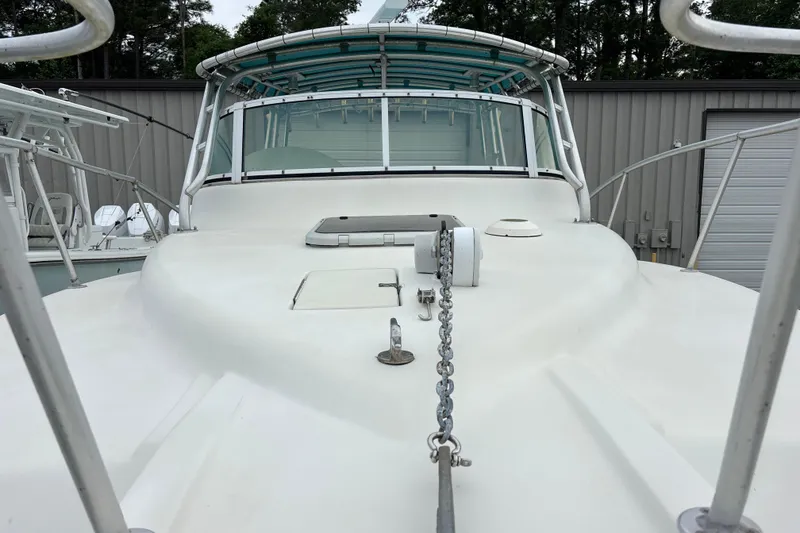 Slide: The Image of 1998 Hydrocat 300X boat deck with anchor chain and windshield, docked near a metal building. - 19