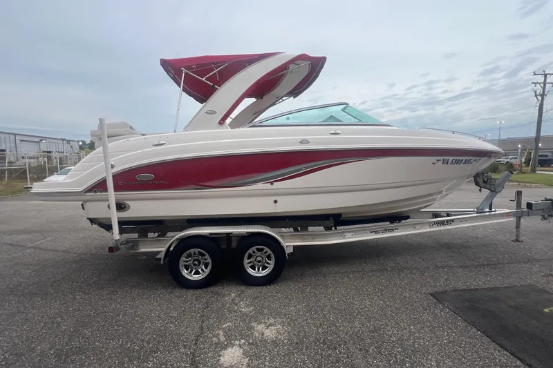 Slide: The Image of 2006 Chaparral 256 SSi boat with red accents on a trailer, parked outdoors. - 10