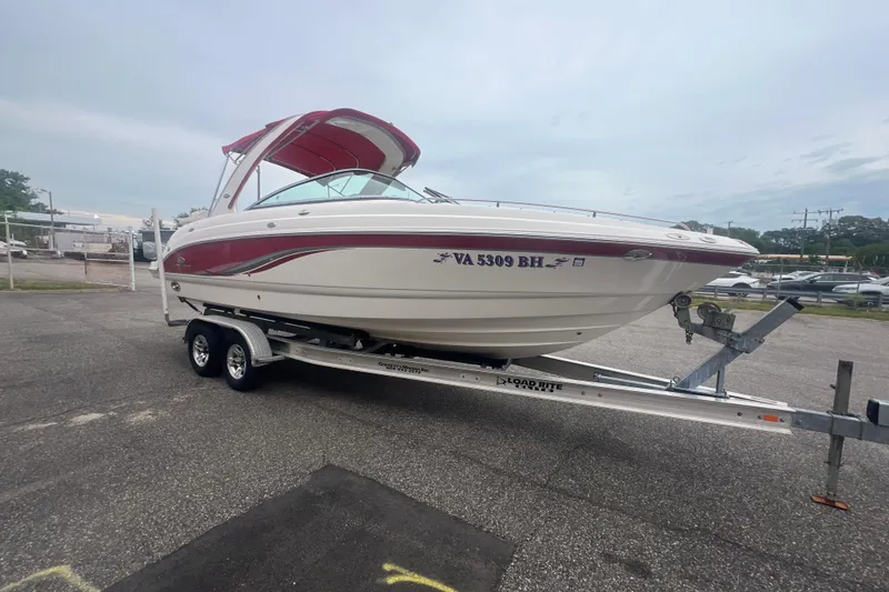 Slide: The Image of 2006 Chaparral 256 SSi boat on trailer, parked outdoors, featuring red and white design. - 12