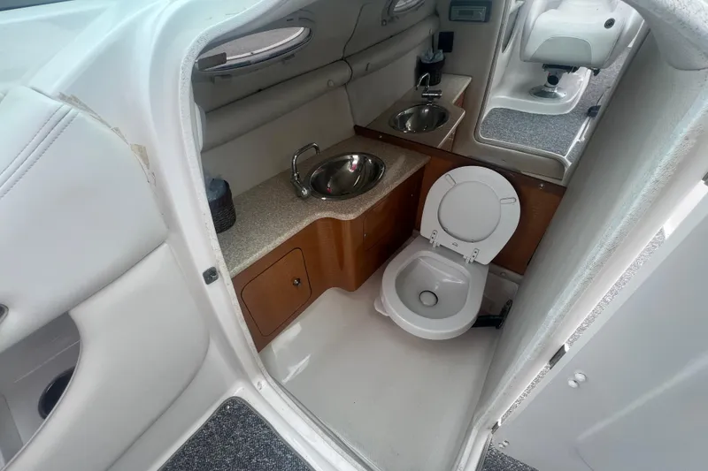 Slide: The Image of 2006 Chaparral 256 SSi boat interior with toilet and sink in compact bathroom. - 22