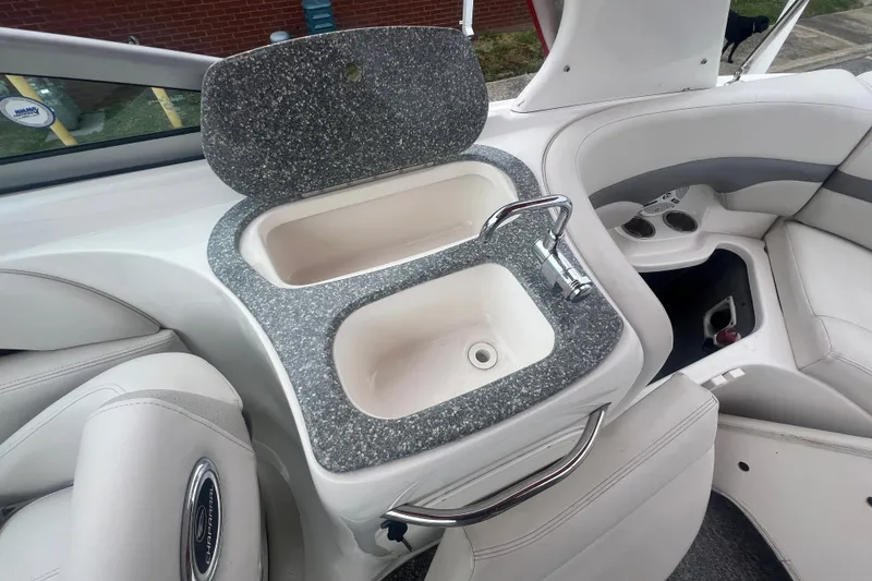 Slide: The Image of 2006 Chaparral 256 SSi boat interior with sink and faucet, featuring white and gray seating. - 34
