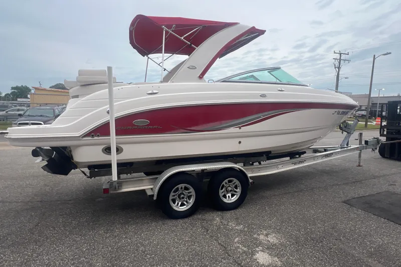Slide: The Image of 2006 Chaparral 256 SSi boat with red accents on a trailer, parked outdoors. - 9