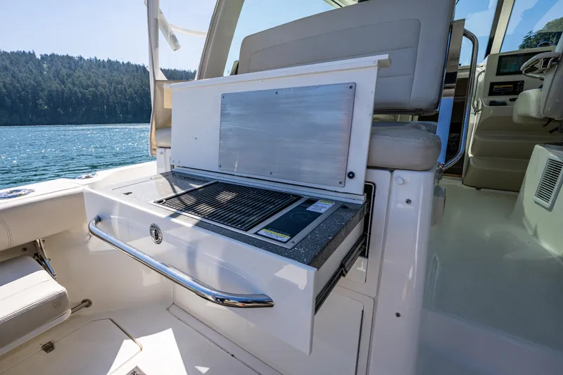 Slide: The Image of 2019 Boston Whaler 345 Conquest boat interior with built-in grill and scenic water view. - 10