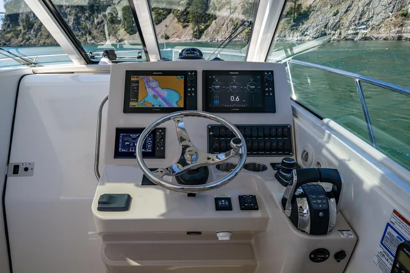Slide: The Image of 2019 Boston Whaler 345 Conquest helm with navigation screens and steering wheel. - 11