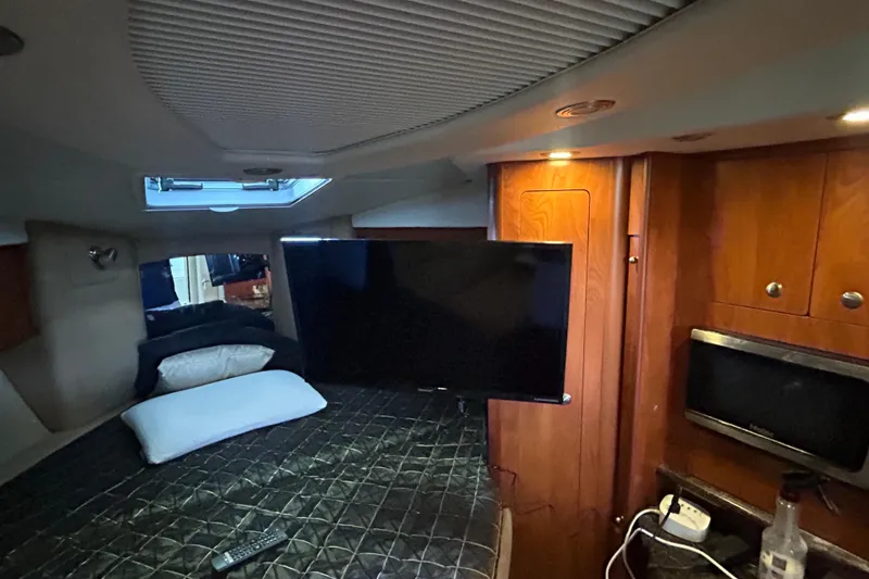 Slide: The Image of Interior of 2013 Rinker 310 Express Cruiser with bed, TV, and wooden cabinetry. - 16