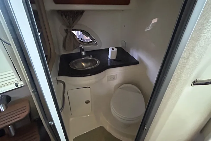 Slide: The Image of 2013 Rinker 310 Express Cruiser bathroom with sink, toilet, and window. - 25