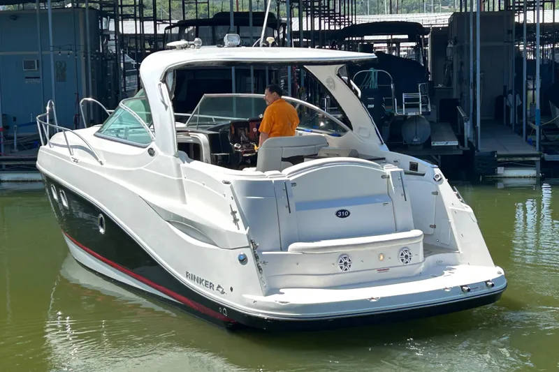 Slide: The Image of 2013 Rinker 310 Express Cruiser docked, featuring sleek design and spacious deck. - 36