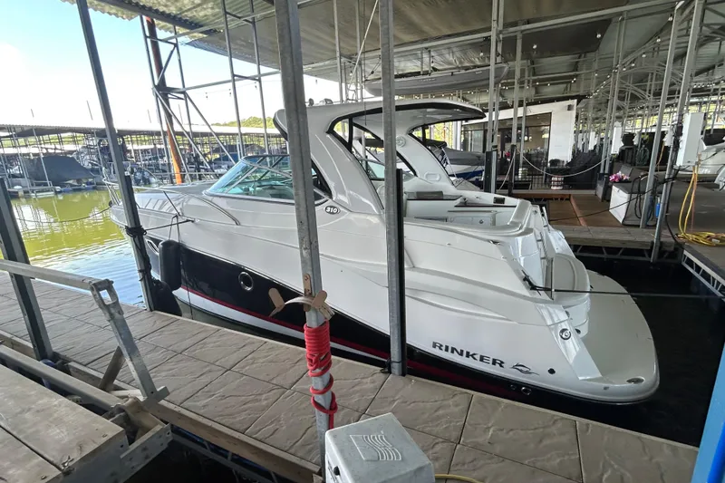 Slide: The Image of 2013 Rinker 310 Express Cruiser docked in a marina, side view. - 47
