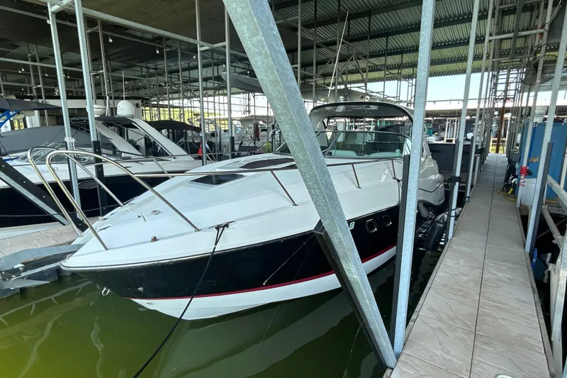 Slide: The Image of 2013 Rinker 310 Express Cruiser docked in a marina under a covered shelter. - 48