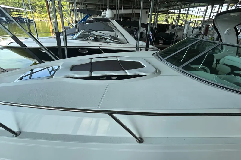 Slide: The Image of 2013 Rinker 310 Express Cruiser docked in a marina, showcasing sleek design and spacious deck. - 49