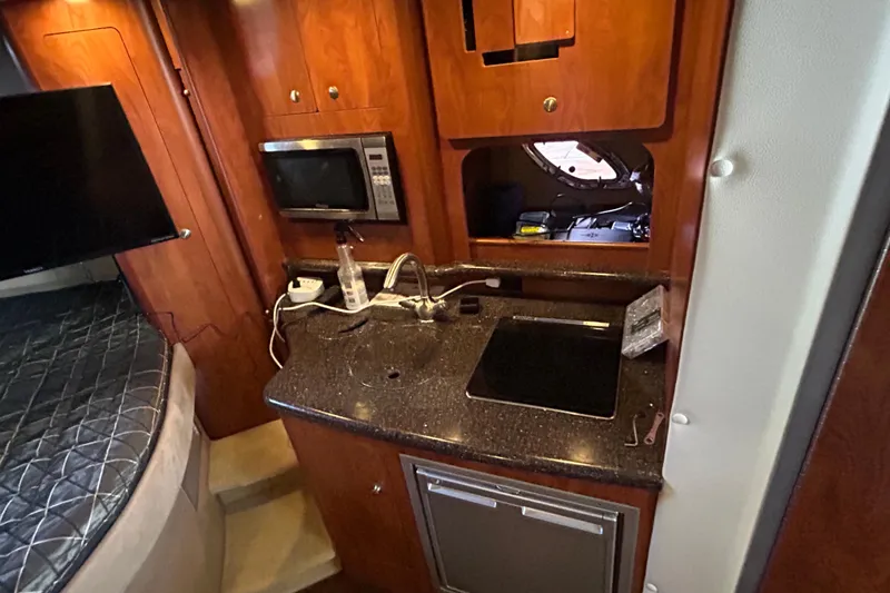 Slide: The Image of 2013 Rinker 310 Express Cruiser interior with kitchenette, microwave, and bed. - 56