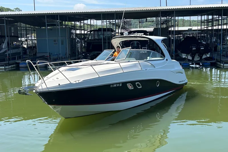 Slide: The Image of 2013 Rinker 310 Express Cruiser docked in marina, sleek design, calm water. - 61