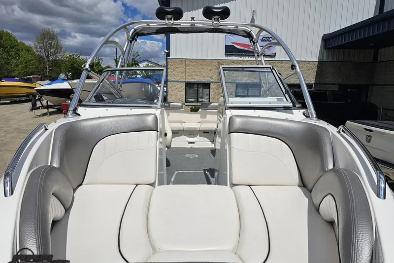 Slide: The Image of 2007 Yamaha Boats AR230 HO interior with white and gray seating, parked outdoors. - 14