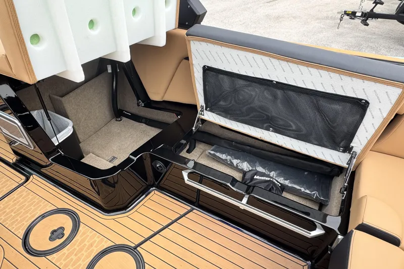 Slide: The Image of 2025 MasterCraft X26 boat interior storage compartments with tan upholstery and black accents. - 18