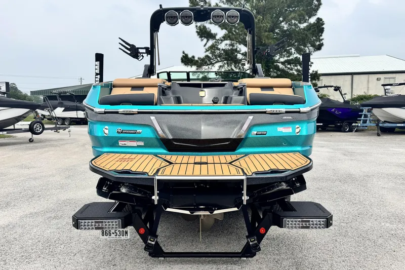 Slide: The Image of 2025 MasterCraft X26 boat, rear view, teal color, parked outdoors. - 4