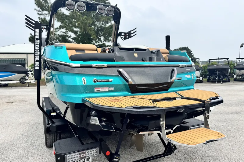 Slide: The Image of 2025 MasterCraft X26 boat with teal exterior and wooden deck, parked on a trailer. - 5