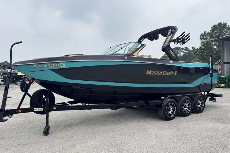 Slide: The Image of 2025 MasterCraft X26 boat on trailer, sleek design, black and teal color scheme. - 7
