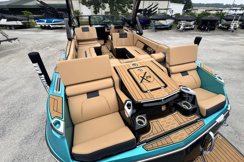 Slide: The Image of 2025 MasterCraft X26 boat with luxurious tan seating and sleek design in a showroom. - 8