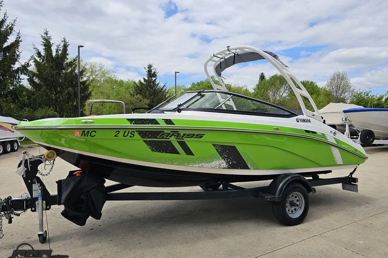 Slide: The Image of 2022 Yamaha AR195 boat in vibrant green on a trailer, parked outdoors. - 22