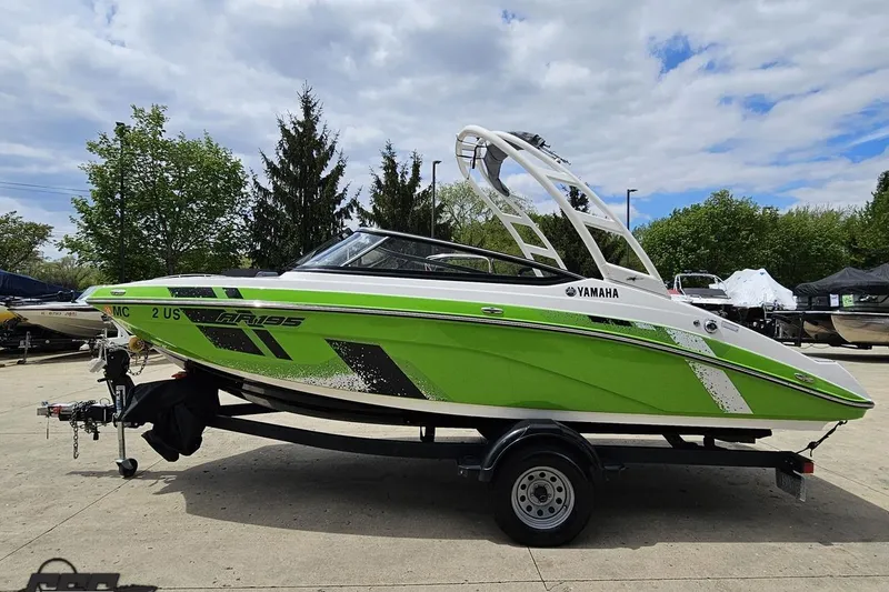 Slide: The Image of 2022 Yamaha AR195 boat in vibrant green on trailer, parked outdoors under cloudy sky. - 23