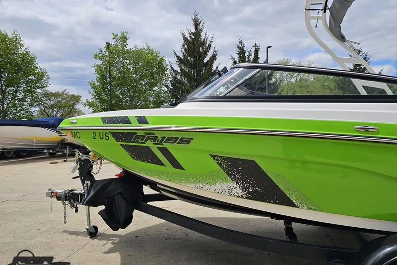 Slide: The Image of 2022 Yamaha Boats AR195 in vibrant green on a trailer, parked outdoors. - 24