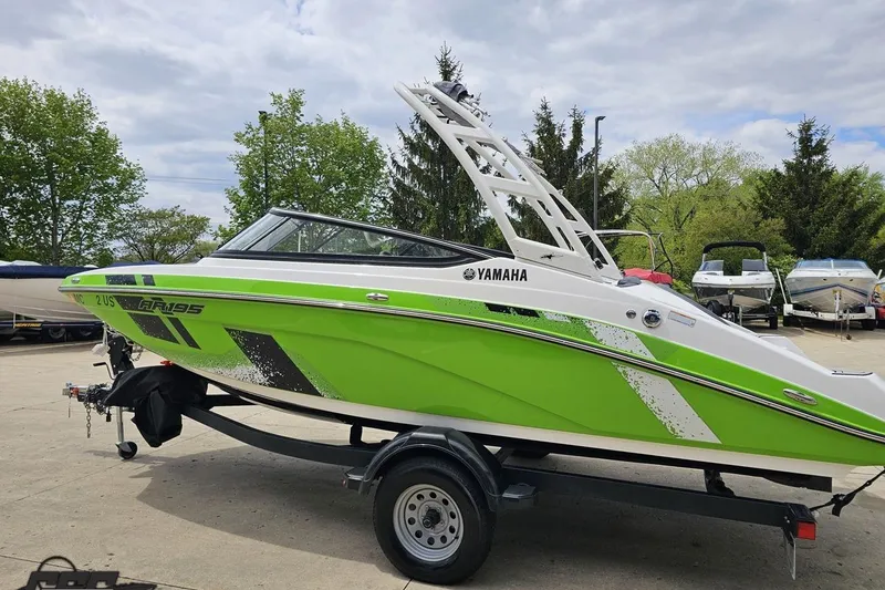 Slide: The Image of 2022 Yamaha Boats AR195 in vibrant green on a trailer, parked outdoors. - 28
