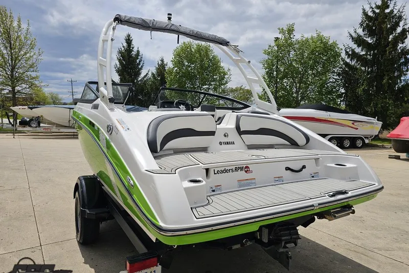 Slide: The Image of 2022 Yamaha Boats AR195 with green accents, parked outdoors on a trailer. - 31