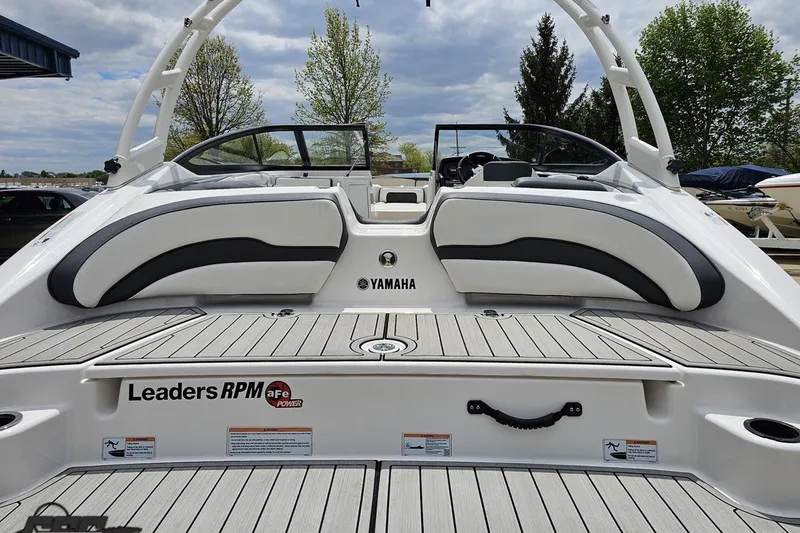 Slide: The Image of 2022 Yamaha Boats AR195, rear view with seating and deck, under cloudy sky. - 35