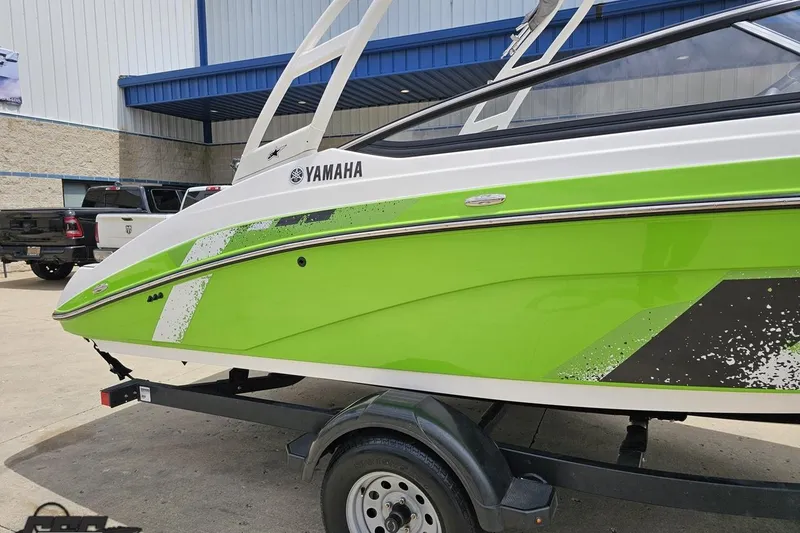 Slide: The Image of 2022 Yamaha AR195 boat in vibrant green on a trailer outside a building. - 5