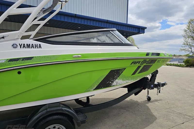 Slide: The Image of 2022 Yamaha AR195 boat in vibrant green on a trailer, parked outdoors. - 6