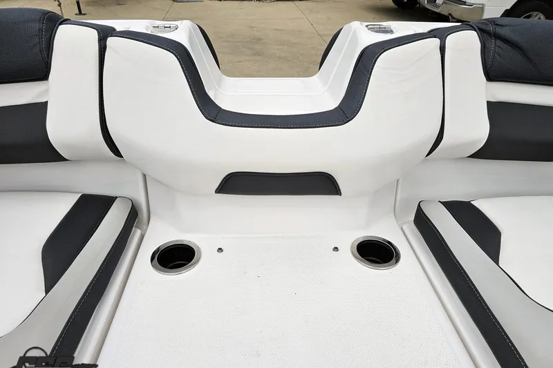 Slide: The Image of 2022 Yamaha Boats AR195 interior seating with cup holders, featuring sleek white and black design. - 85