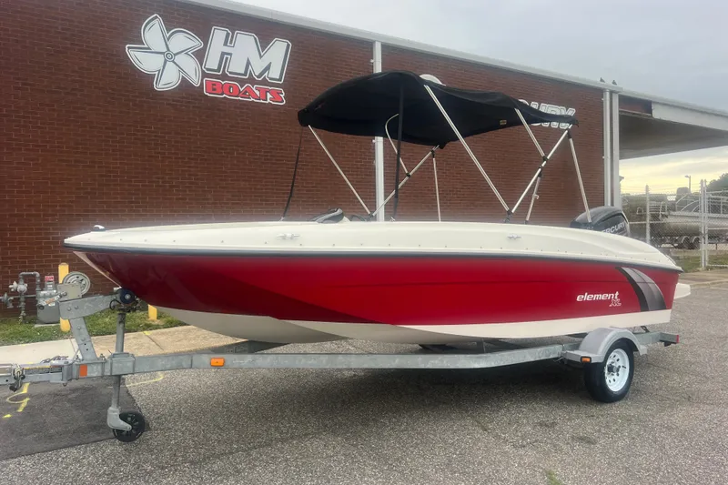The Image of 2015 Bayliner Element XL boat with red hull on trailer, parked outside HM Boats building. - 0