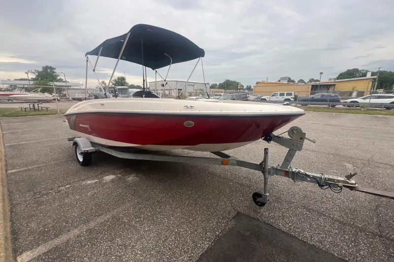 Slide: The Image of 2015 Bayliner Element XL boat with red hull on trailer in parking lot. - 10