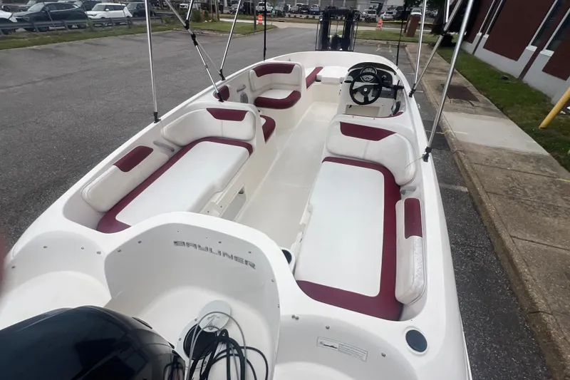 Slide: The Image of 2015 Bayliner Element XL boat with white and maroon seating, parked outdoors. - 13