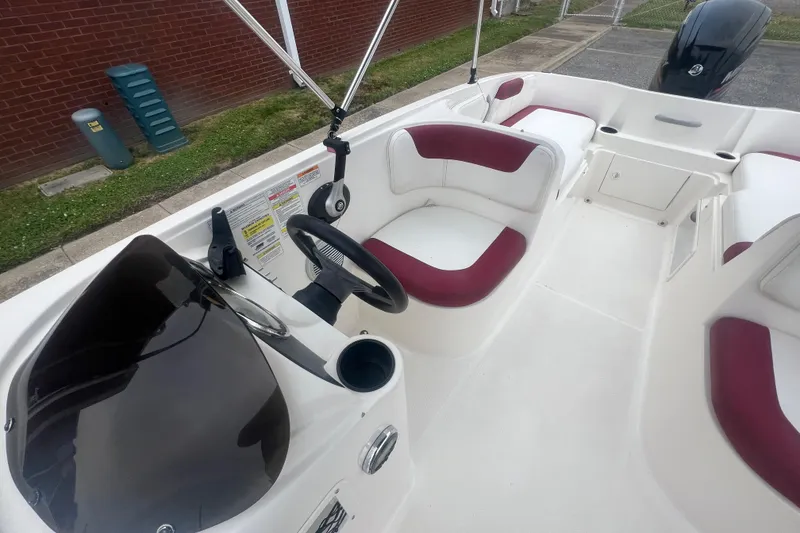 Slide: The Image of 2015 Bayliner Element XL boat interior with maroon and white seating, steering wheel, and controls. - 17