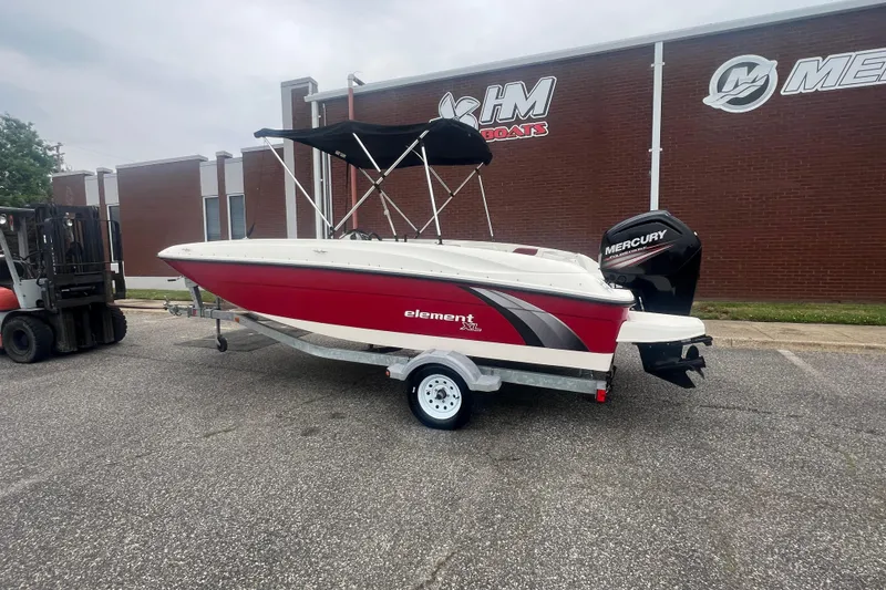 Slide: The Image of 2015 Bayliner Element XL boat with Mercury engine on trailer, parked outside dealership. - 2