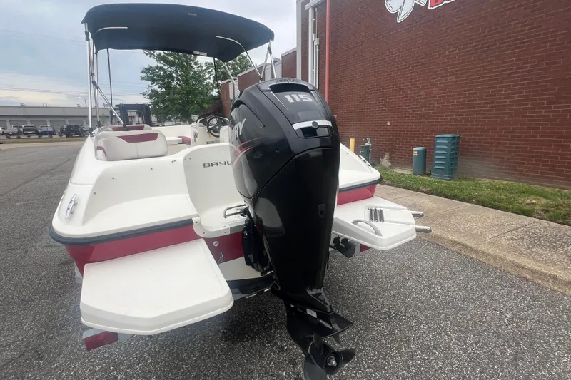 Slide: The Image of 2015 Bayliner Element XL boat with Mercury 115 outboard motor, parked near a brick building. - 4