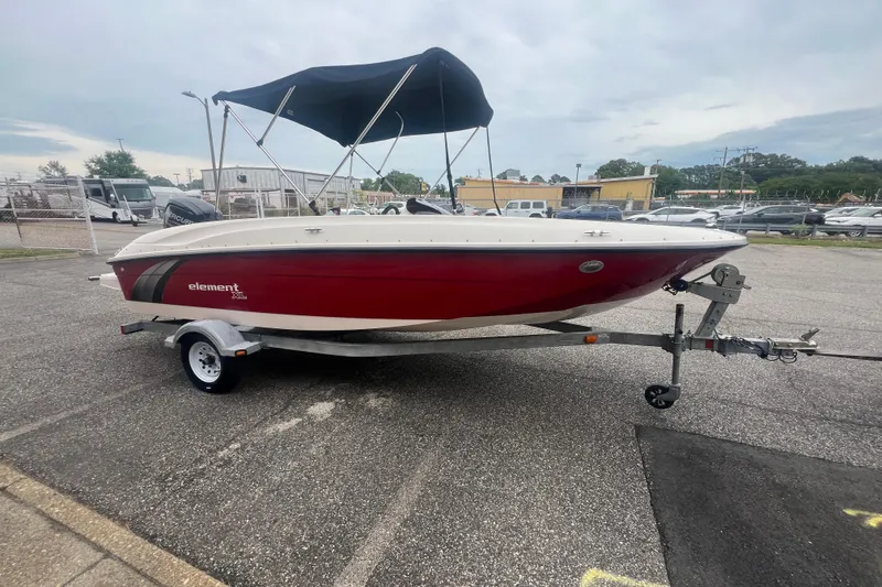 Slide: The Image of 2015 Bayliner Element XL boat with red hull on a trailer, parked outdoors. - 9