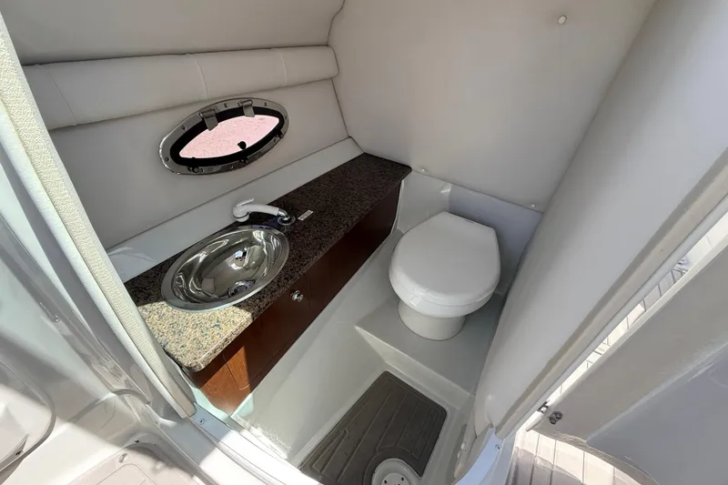 Slide: The Image of 2018 Crownline Eclipse E26 XS boat bathroom with sink, toilet, and porthole window. - 20