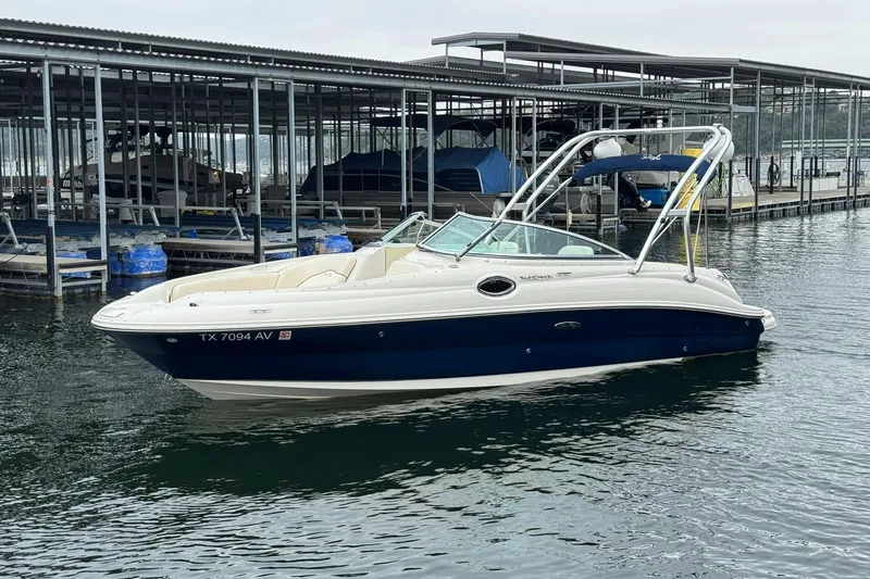 The Image of 2008 Sea Ray 240 Sundeck boat docked in marina, featuring sleek design and blue hull. - 0