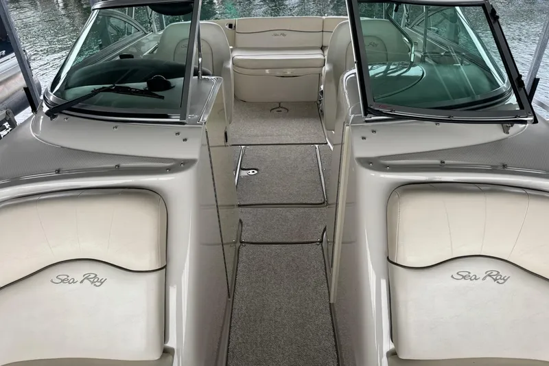 Slide: The Image of 2008 Sea Ray 240 Sundeck interior with seating and windshield, docked by the water. - 23