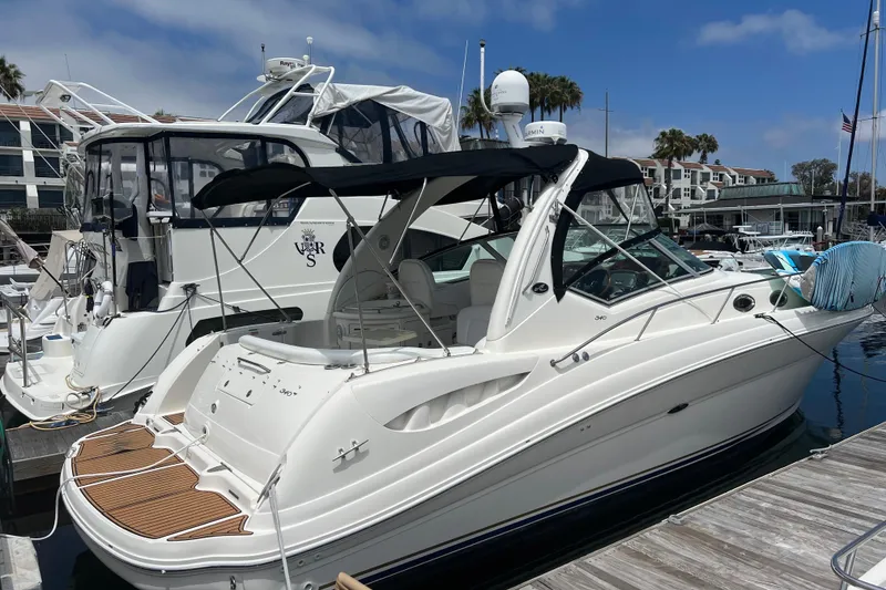 The Image of 2003 Sea Ray 340 Sundancer docked at a marina under a clear blue sky. - 0