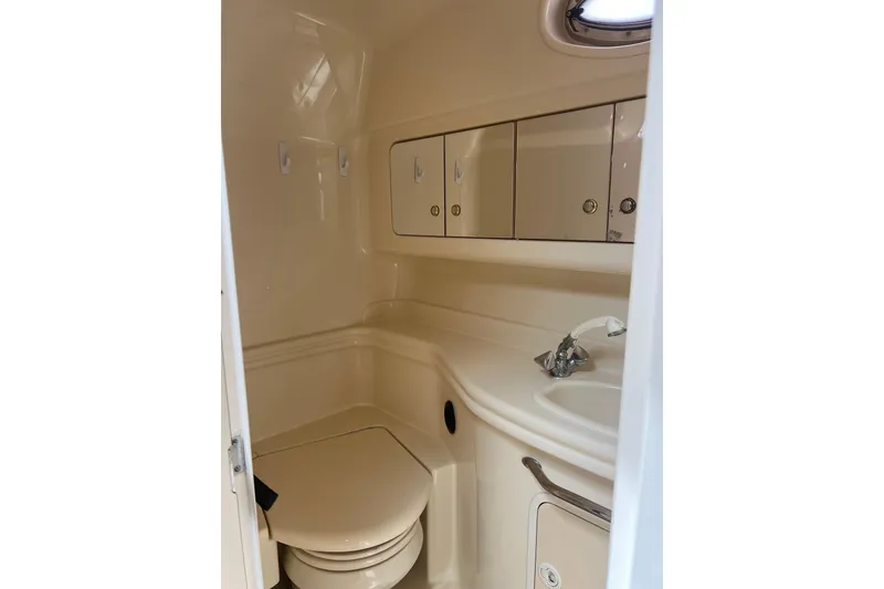 Slide: The Image of 2003 Sea Ray 340 Sundancer bathroom with sink, storage cabinets, and compact toilet. - 18
