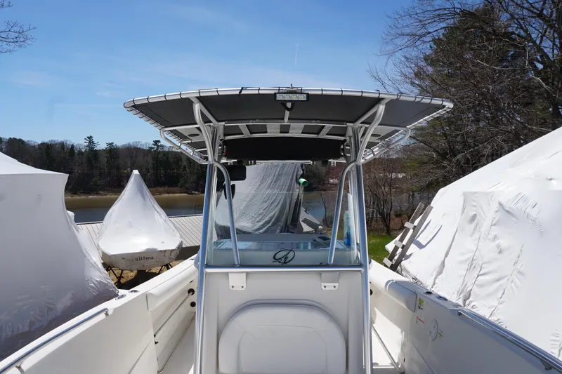 Slide: The Image of 2012 Sailfish 2380 CC boat with T-top, docked near covered vessels, scenic background. - 12